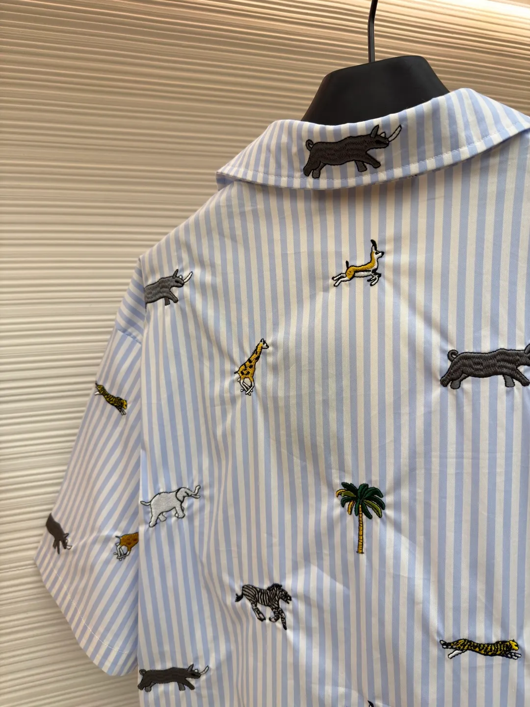 LOUIS VUITTON nostalgic style embroidered striped short-sleeved shirt with animals and plants ●Original version: Purchased and developed by 16815 ●Item number: 1682514-A65 ●Fabric: cotton fabric ●Technology: embroidery production ●Color: blue ●Version: fitted version ●Weight: about 220 grams ●Size: S-M-L-XL ●Description: This LOUIS VUITTON striped animal embroidery short-sleeved shirt is made of high-count pure cotton poplin fabric. After pre-washing process, it feels smooth and breathable. It has both drape and stiffness, and is not easy to wrinkle and deform. The blue and white vertical stripes on the body are woven with yarn-dyed technology, and the texture is clear and does not fade. The animal and coconut tree patterns are presented with sophisticated embroidery technology. The embroidery threads are full of color and the stitches are dense. The patterns are three-dimensional and vivid, forming a rich visual hierarchy with the stripe base. The shirt has a Cuban collar style, with smooth necklines, custom mother-of-pearl buttons at the placket, and a warm texture. The overall shape is loose, the shoulder joints are straight and fine, the cuffs are cuffed with exquisite craftsmanship, custom accessories and three logos are complete, and the details are full of luxury craftsmanship. It is suitable for casual vacations and daily outings, etc. The overall wiring is straight and delicate, the fabric is comfortable and soft, and the color is consistent without color difference. It can be matched with the same style to create a fashionable look and control various occasions. Customized accessories, complete with three standards, same style for men and women!